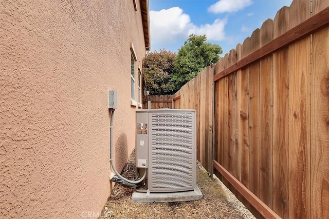 details featuring central AC, fence, and stucco siding