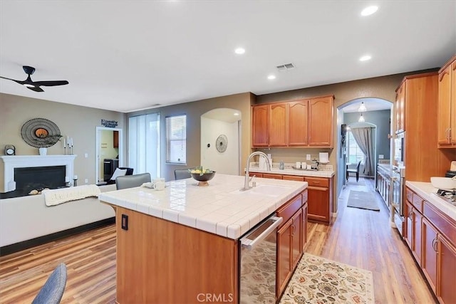 kitchen featuring light wood-type flooring, a ceiling fan, visible vents, appliances with stainless steel finishes, and arched walkways