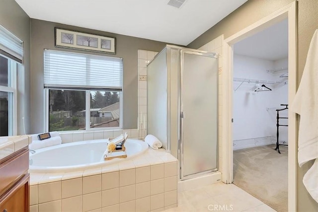 full bathroom with a spacious closet, a bath, and a stall shower