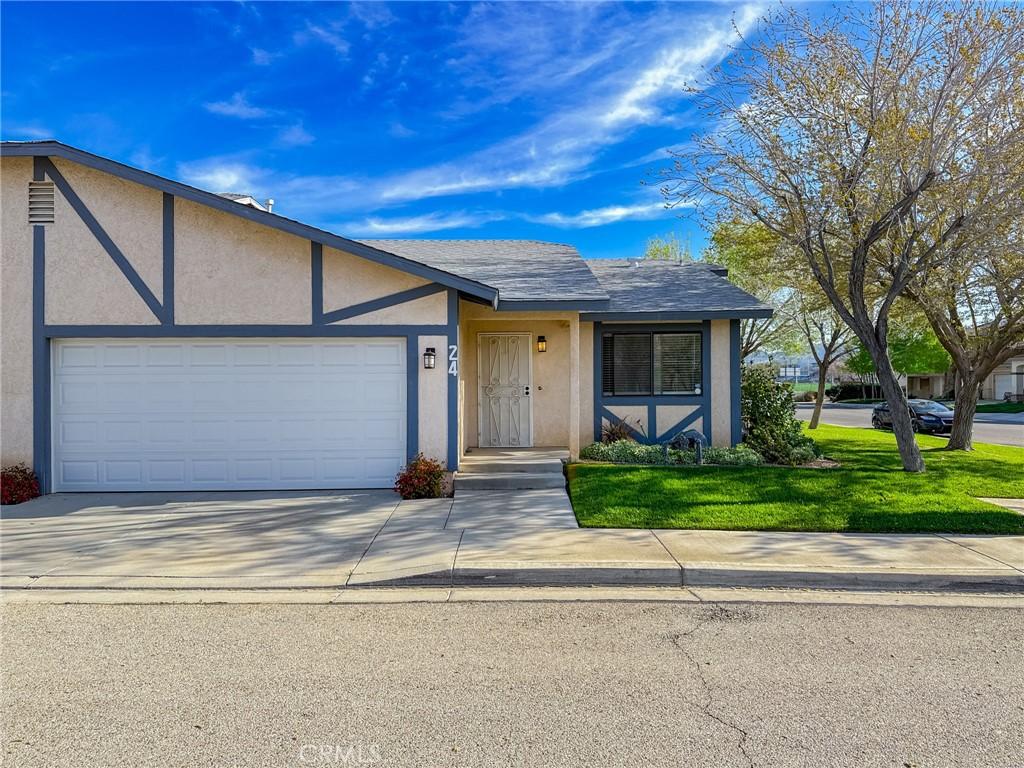 43840 Bobby Jones Dr Unit 24, Lancaster, CA 93536 - view of front of property featuring concrete driveway, roof with shingles, stucco siding, an attached garage, and a front yard