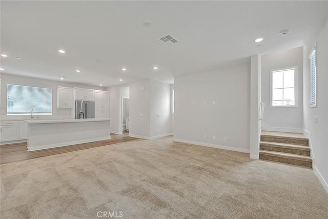 6 Crown Point Dr, Rancho Mission Viejo, CA 92694 - unfurnished living room featuring recessed lighting, stairway, visible vents, light colored carpet, and a sink