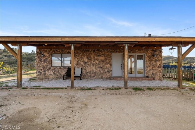 rear view of property featuring french doors and stone siding