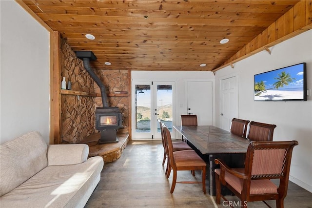 dining area featuring french doors, a wood stove, wood finished floors, and wood ceiling