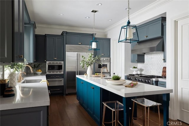 kitchen featuring ventilation hood, light countertops, blue cabinetry, and built in appliances