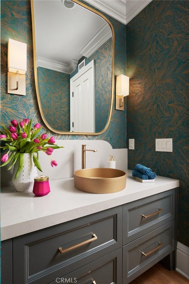bathroom with wallpapered walls, vanity, and ornamental molding