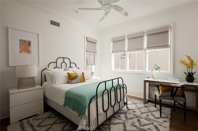 bedroom featuring baseboards, crown molding, a ceiling fan, visible vents, and wood finished floors