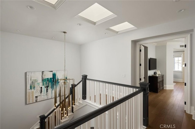 hall featuring dark wood finished floors, visible vents, baseboards, recessed lighting, and an upstairs landing