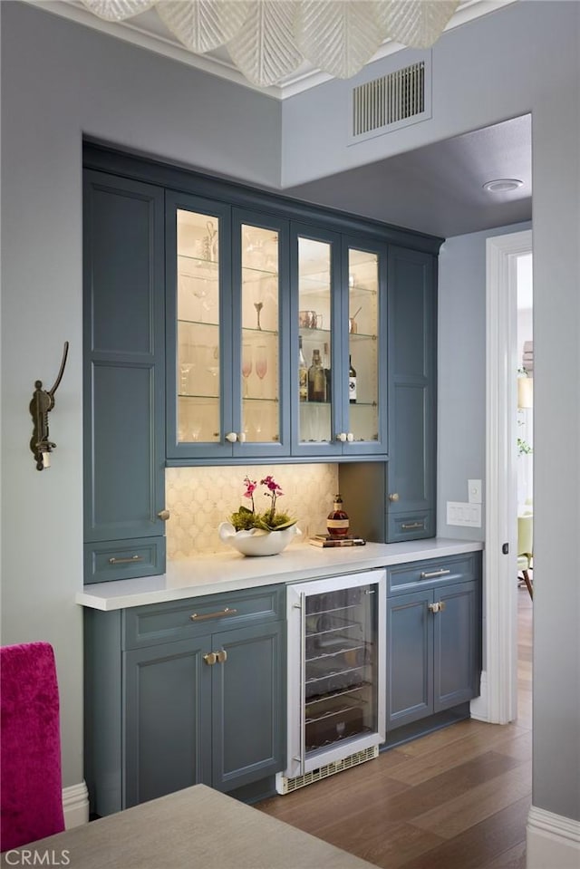 bar with tasteful backsplash, visible vents, dark wood-style flooring, a dry bar, and beverage cooler
