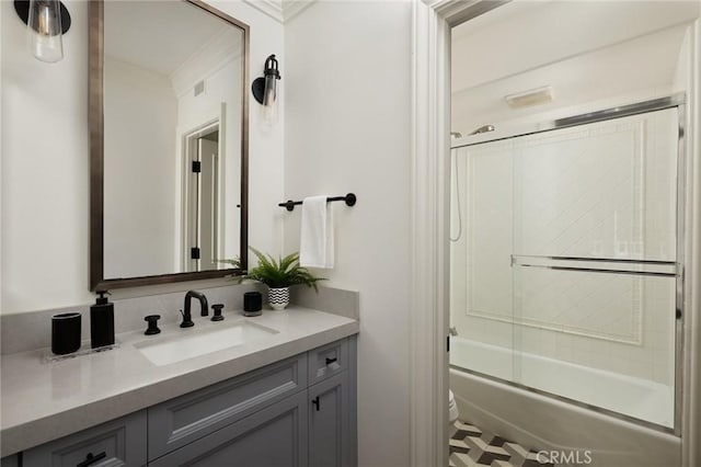 bathroom featuring crown molding, toilet, vanity, and shower / bath combination with glass door