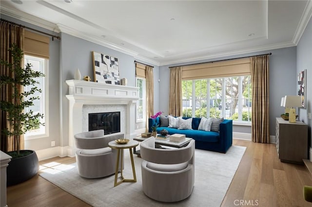 living area featuring a premium fireplace, baseboards, wood finished floors, and ornamental molding