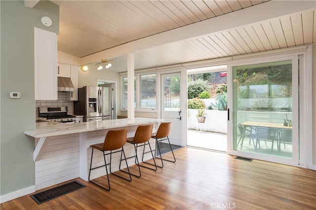 1503 Calle Sacramento, San Clemente, CA 92672 - kitchen with appliances with stainless steel finishes, under cabinet range hood, white cabinetry, light stone countertops, and a peninsula