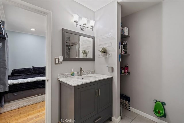 bathroom with ensuite bathroom, baseboards, tile patterned flooring, and vanity