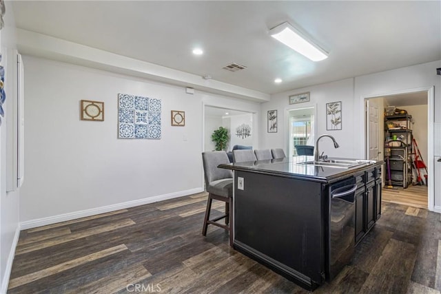kitchen featuring dark cabinets, dark wood-style flooring, visible vents, and a sink