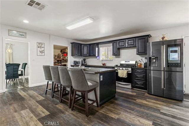 kitchen with visible vents, a sink, a kitchen breakfast bar, dark wood finished floors, and stainless steel appliances