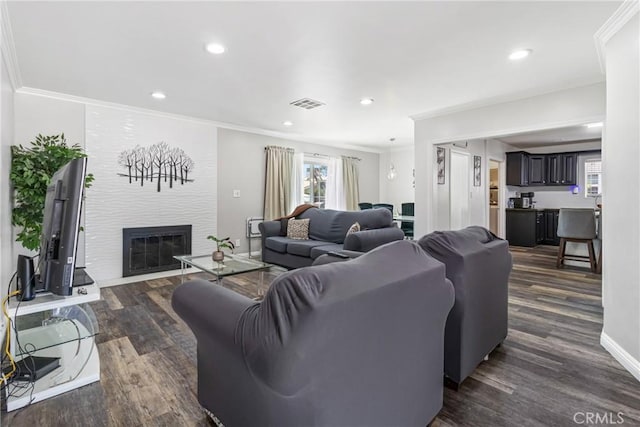 living room featuring ornamental molding, visible vents, a large fireplace, and dark wood-type flooring