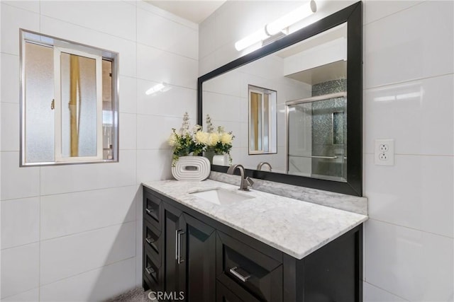 bathroom featuring a shower stall, vanity, and tile walls