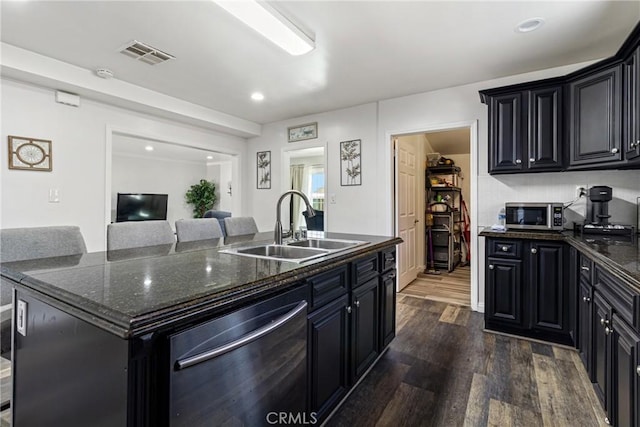 kitchen with visible vents, a sink, a kitchen island with sink, dark wood finished floors, and stainless steel appliances