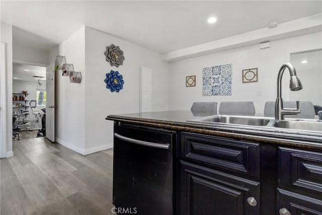 kitchen featuring dark countertops, a sink, black dishwasher, and wood finished floors