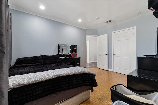 bedroom with crown molding, light wood finished floors, visible vents, and recessed lighting