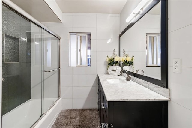 bathroom with shower / bath combination with glass door, vanity, and tile walls