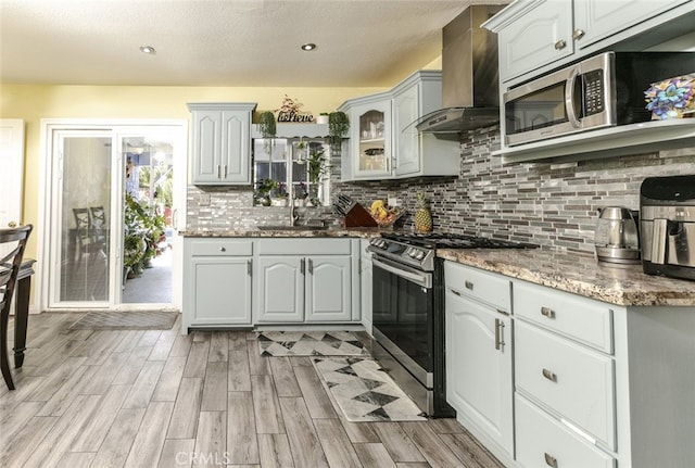610 Woodington Dr, Lancaster, CA 93535 - kitchen with stainless steel appliances, wall chimney exhaust hood, a sink, tasteful backsplash, and light wood-type flooring