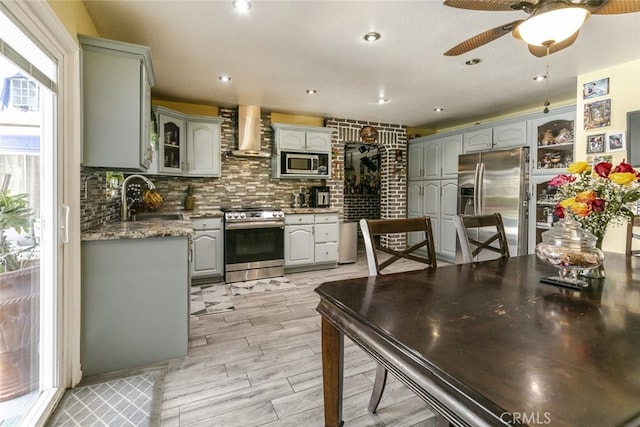 610 Woodington Dr, Lancaster, CA 93535 - kitchen with stainless steel appliances, wall chimney exhaust hood, a sink, gray cabinets, and glass insert cabinets