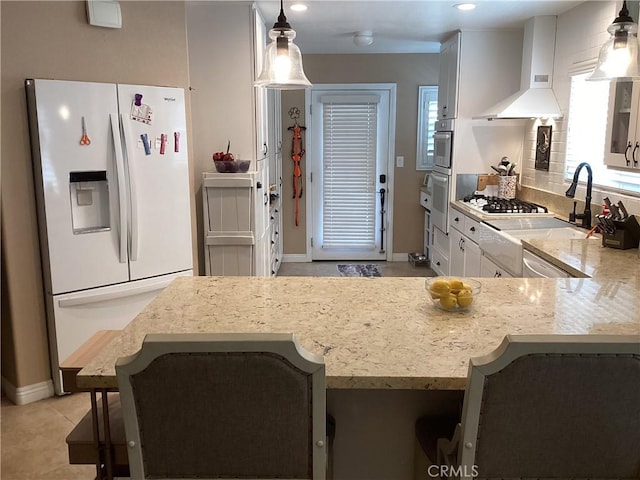 23796 Corte Picante, Murrieta, CA 92562 - kitchen with pendant lighting, wall chimney range hood, white cabinets, light stone counters, and stainless steel appliances