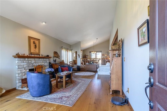 7191 Slater Ave, Huntington Beach, CA 92647 - living room featuring a chandelier, light wood-type flooring, a stone fireplace, and vaulted ceiling