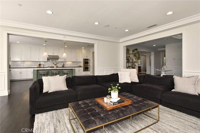living area featuring a wainscoted wall, visible vents, dark wood finished floors, and a decorative wall