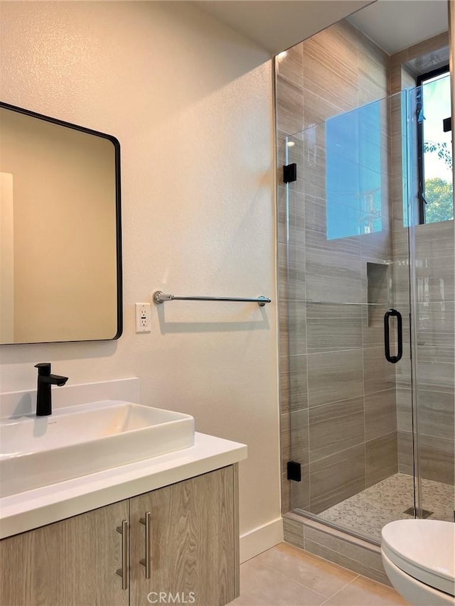 full bath featuring baseboards, toilet, vanity, tile patterned floors, and a stall shower