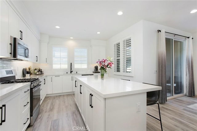 83 Hideaway Loop, Mission Viejo, CA 92692 - kitchen with appliances with stainless steel finishes, a sink, a breakfast bar, light wood-style flooring, and backsplash