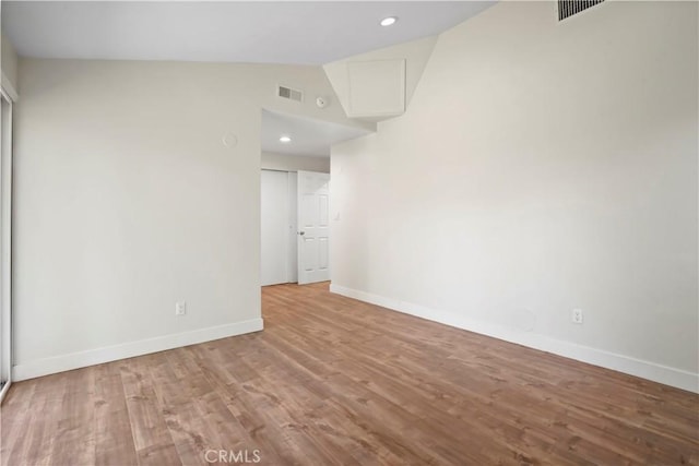unfurnished room featuring visible vents, baseboards, wood finished floors, and lofted ceiling