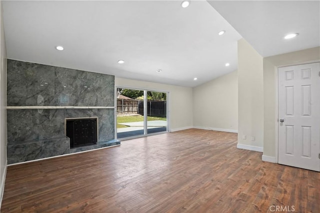 unfurnished living room featuring baseboards, recessed lighting, a premium fireplace, and wood finished floors