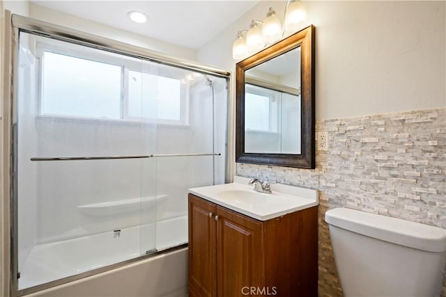 full bath with toilet, vanity, and bath / shower combo with glass door