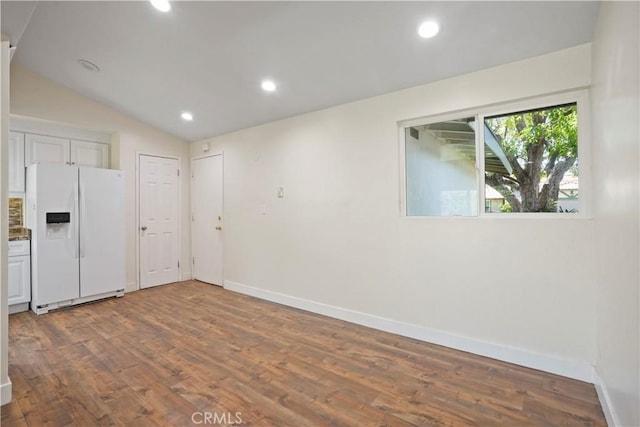 empty room featuring wood finished floors, baseboards, lofted ceiling, and recessed lighting