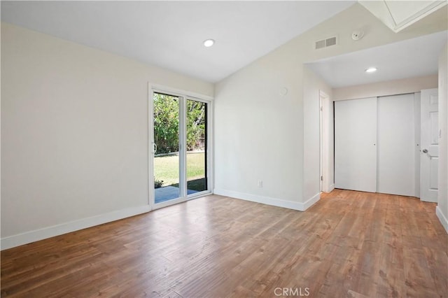 unfurnished room with visible vents, baseboards, wood finished floors, and lofted ceiling