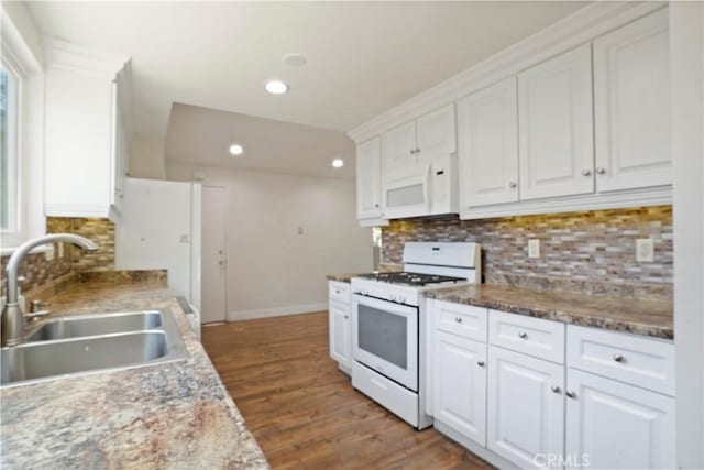 kitchen featuring white cabinets, a sink, dark wood-style flooring, white appliances, and decorative backsplash