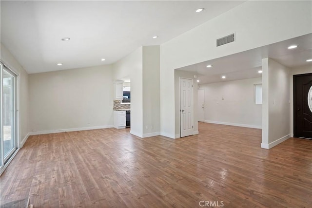 unfurnished living room with light wood-style flooring, baseboards, visible vents, and recessed lighting