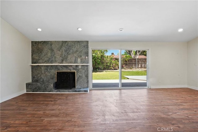unfurnished living room with recessed lighting, a tile fireplace, baseboards, and wood finished floors