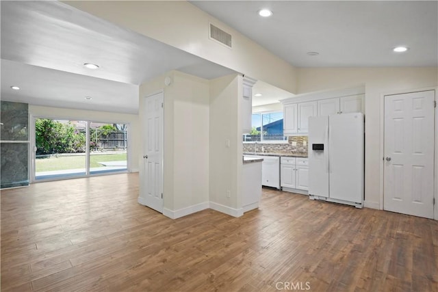 kitchen with white appliances, white cabinetry, visible vents, lofted ceiling, and wood finished floors