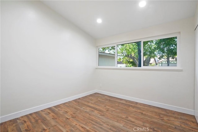 spare room featuring baseboards, recessed lighting, vaulted ceiling, and wood finished floors