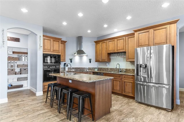 7922 Los Palmas Dr, Oak Hills, CA 92344 - kitchen featuring stone countertops, black appliances, wall chimney exhaust hood, light wood finished floors, and a sink