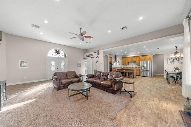 7922 Los Palmas Dr, Oak Hills, CA 92344 - living room featuring visible vents, baseboards, arched walkways, and ceiling fan with notable chandelier