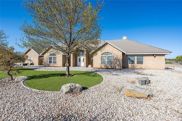 7922 Los Palmas Dr, Oak Hills, CA 92344 - view of front of home with a tiled roof, a chimney, a front lawn, and stucco siding