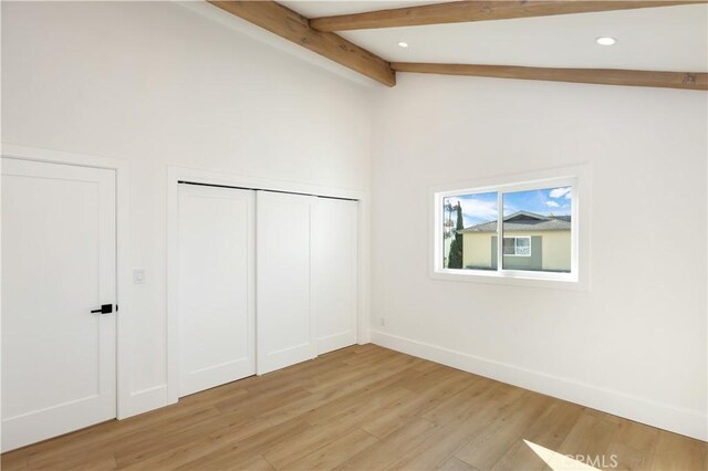 unfurnished bedroom featuring recessed lighting, lofted ceiling with beams, a closet, light wood finished floors, and baseboards