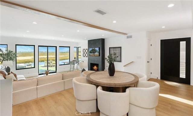 dining room with recessed lighting, a large fireplace, visible vents, and light wood-style flooring