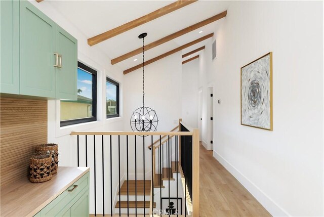 hallway featuring an inviting chandelier, lofted ceiling with beams, an upstairs landing, light wood-type flooring, and visible vents