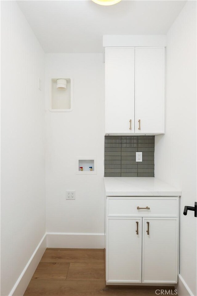 clothes washing area with baseboards, light wood-type flooring, cabinet space, and hookup for a washing machine