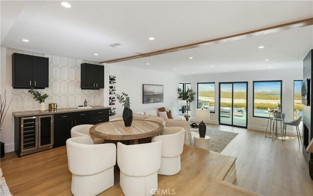 dining space with recessed lighting, light wood-type flooring, indoor wet bar, and wine cooler