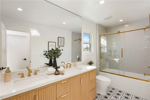 bathroom featuring recessed lighting, a sink, toilet, combined bath / shower with glass door, and double vanity